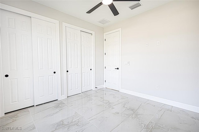 unfurnished bedroom featuring multiple closets and ceiling fan