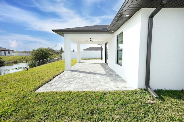 view of patio with a water view and ceiling fan