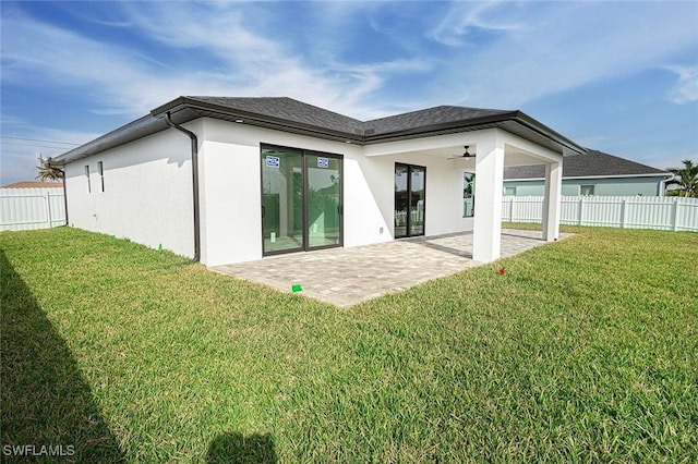 back of property with ceiling fan, a yard, and a patio