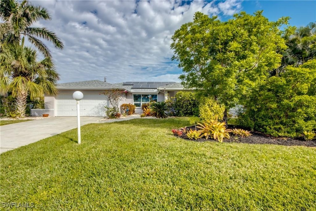 view of front of home featuring a garage, a front lawn, and solar panels