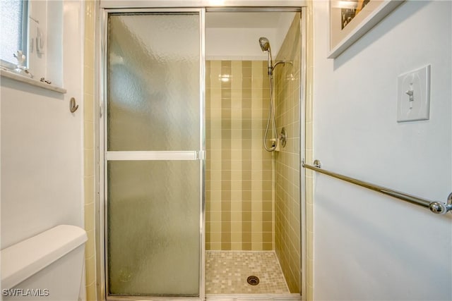 bathroom with toilet and a shower with shower door