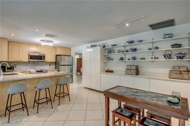 kitchen featuring sink, backsplash, light tile patterned floors, stainless steel appliances, and light brown cabinets