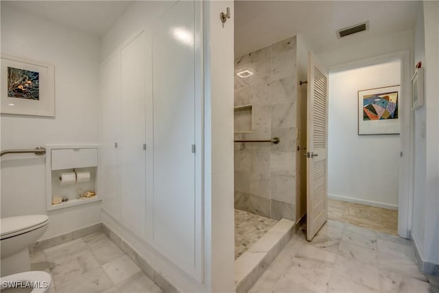 bathroom with toilet and a tile shower