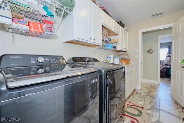 laundry room featuring washing machine and clothes dryer and cabinets