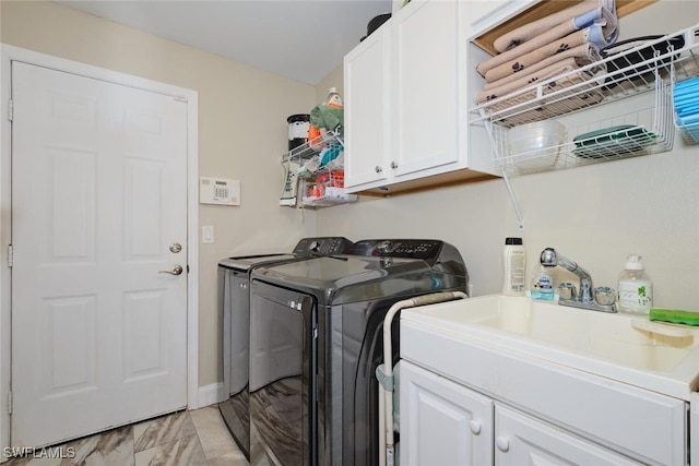 clothes washing area with cabinets and washing machine and clothes dryer