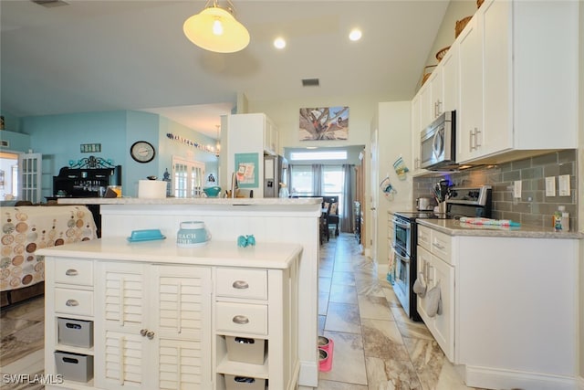 kitchen featuring hanging light fixtures, white cabinets, decorative backsplash, a kitchen island, and appliances with stainless steel finishes