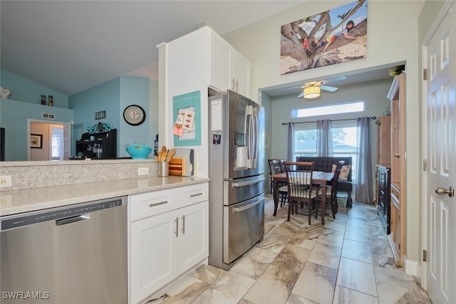 kitchen with light stone countertops, white cabinetry, ceiling fan, stainless steel appliances, and vaulted ceiling