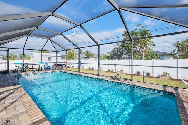 view of swimming pool featuring glass enclosure, a storage unit, and a patio area