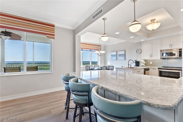 kitchen with kitchen peninsula, tasteful backsplash, range, white cabinetry, and hanging light fixtures