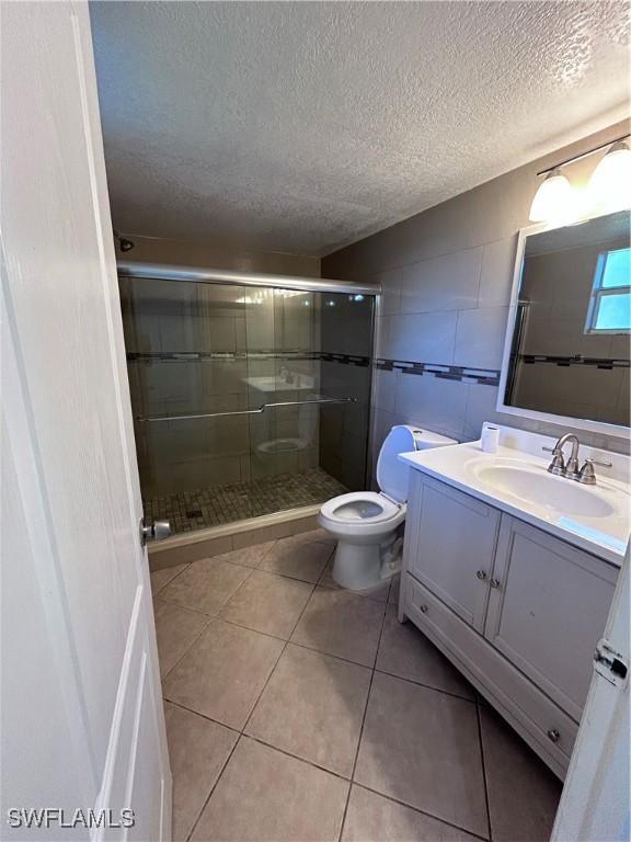 bathroom featuring vanity, toilet, a textured ceiling, and walk in shower