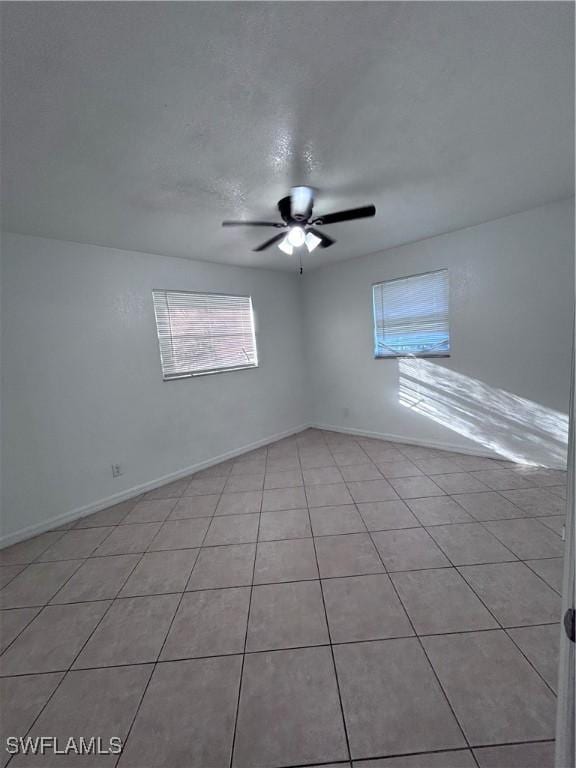 spare room with ceiling fan and light tile patterned flooring