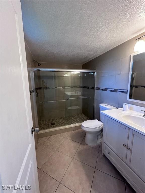 bathroom with a shower with door, vanity, a textured ceiling, and toilet