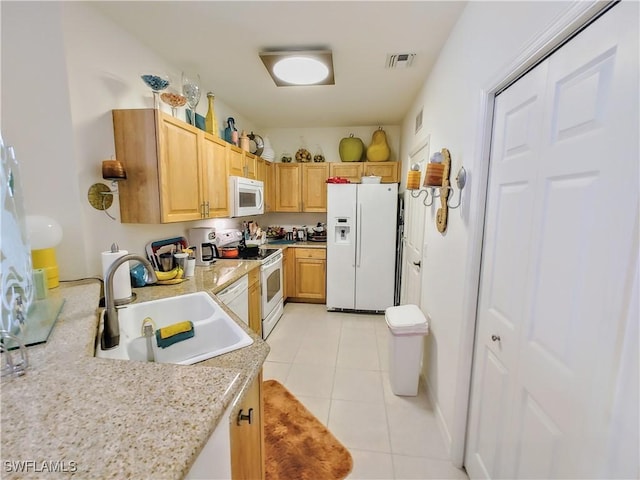 kitchen with light tile patterned flooring, white appliances, sink, and light brown cabinets