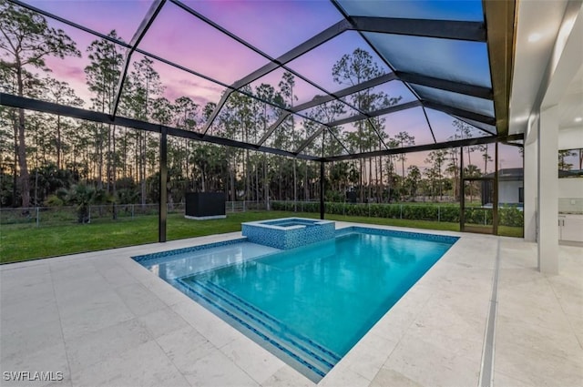 pool at dusk featuring a lawn, glass enclosure, an in ground hot tub, and a patio