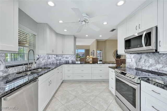 kitchen with dark stone counters, sink, white cabinets, and stainless steel appliances