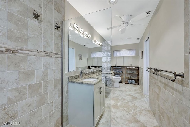 bathroom featuring vanity, tile patterned floors, ceiling fan, toilet, and tile walls