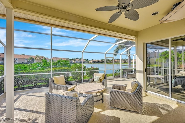 sunroom with plenty of natural light, ceiling fan, and a water view