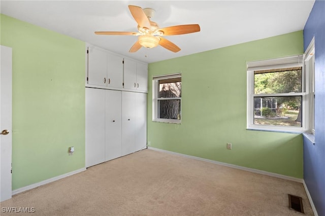 unfurnished bedroom with light carpet, a closet, and ceiling fan