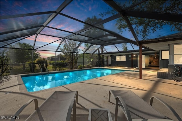 pool at dusk with a lanai and a patio area