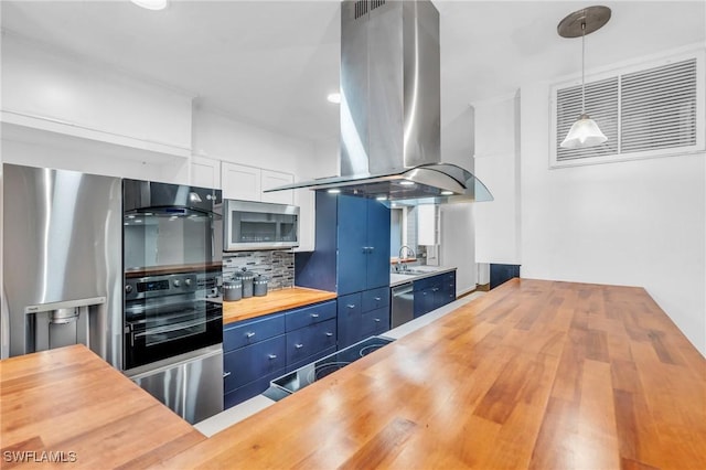 kitchen featuring wood counters, island exhaust hood, stainless steel appliances, blue cabinetry, and hanging light fixtures