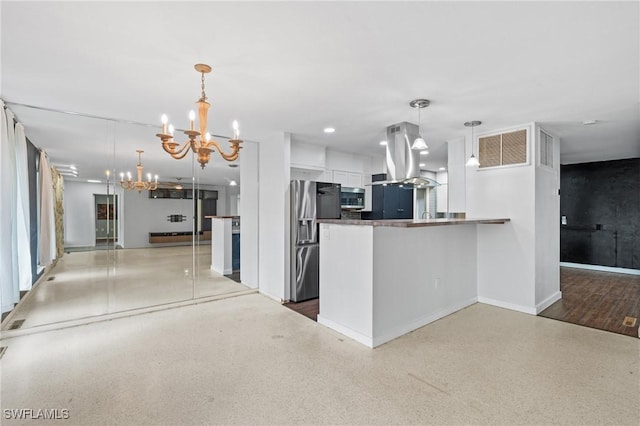 kitchen featuring white cabinets, hanging light fixtures, appliances with stainless steel finishes, a notable chandelier, and kitchen peninsula