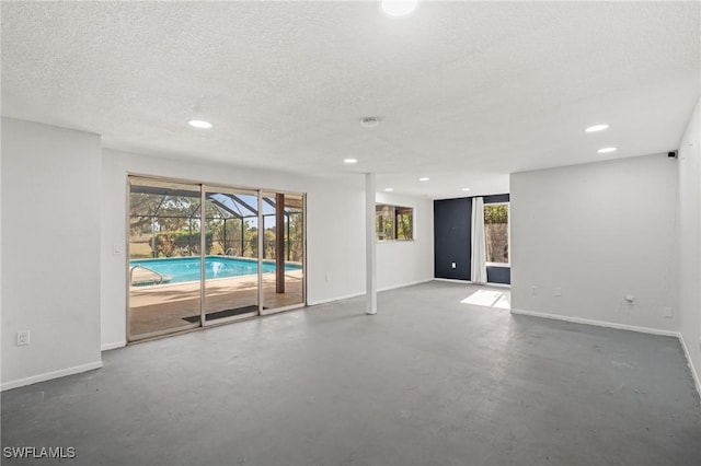 unfurnished room with a textured ceiling, concrete floors, and plenty of natural light