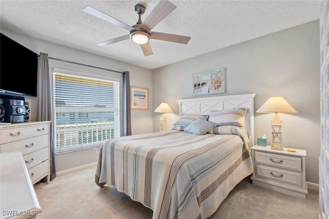 bedroom with a textured ceiling, ceiling fan, and light carpet