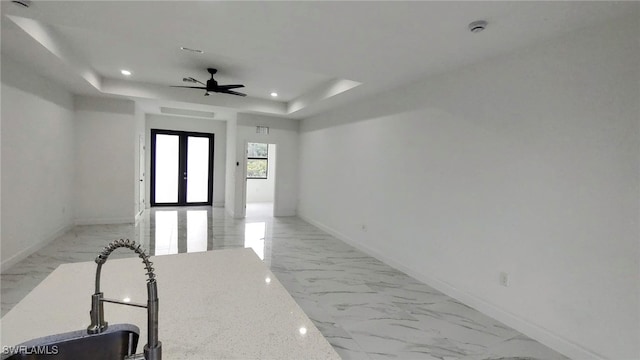 hallway featuring french doors, a tray ceiling, and sink