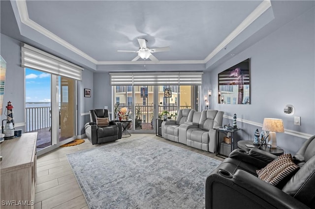 living room featuring a tray ceiling, ceiling fan, and crown molding