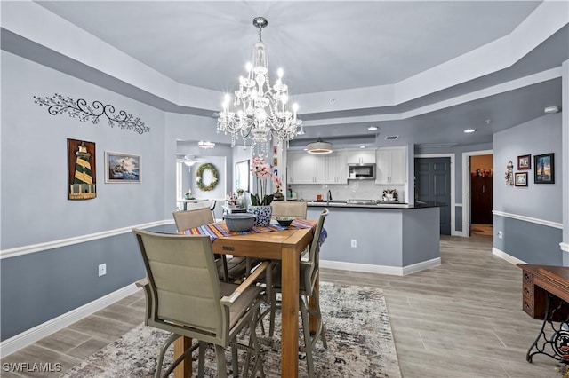 dining space with a tray ceiling and an inviting chandelier