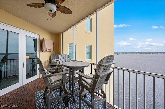 balcony with ceiling fan and a water view