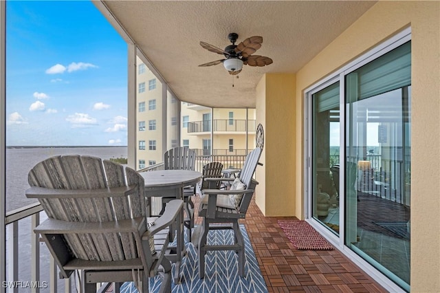 balcony featuring a water view and ceiling fan