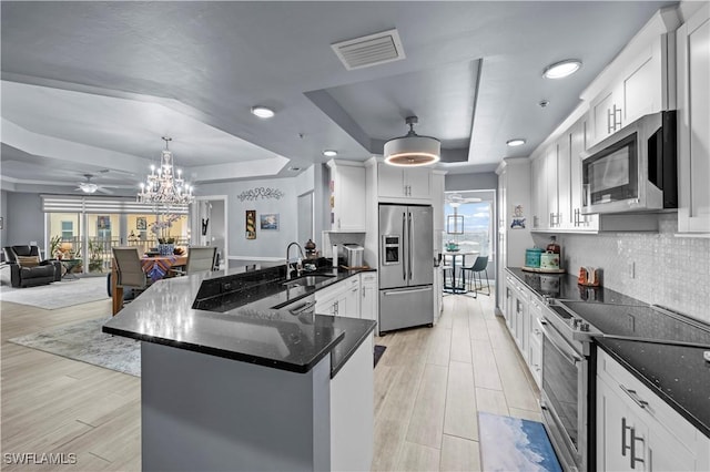 kitchen featuring white cabinets, sink, stainless steel appliances, and a tray ceiling