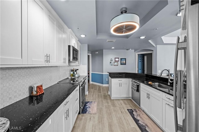 kitchen with dark stone countertops, white cabinetry, sink, and stainless steel appliances