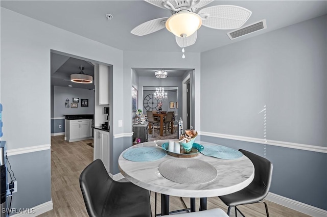 dining space featuring ceiling fan with notable chandelier and light wood-type flooring