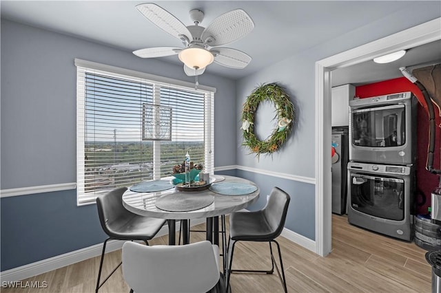 dining space featuring light hardwood / wood-style flooring, stacked washer / dryer, and ceiling fan