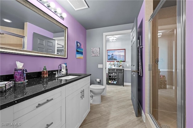 bathroom featuring vanity, wood-type flooring, an enclosed shower, and toilet