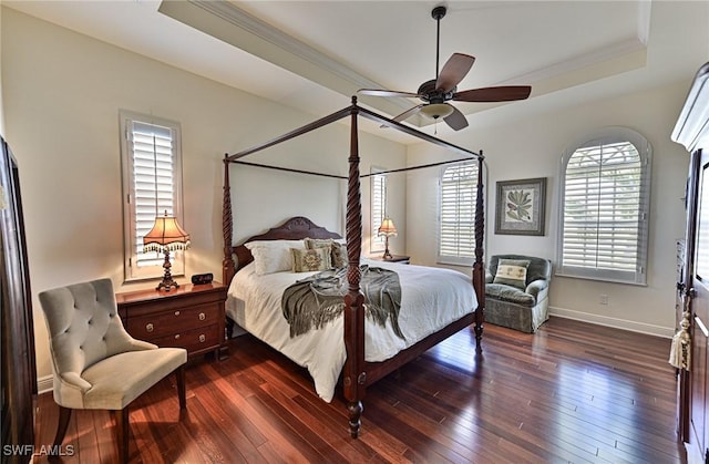 bedroom featuring a raised ceiling, crown molding, dark wood-type flooring, and ceiling fan