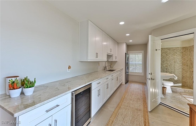 kitchen with white cabinets, stainless steel fridge, sink, and beverage cooler