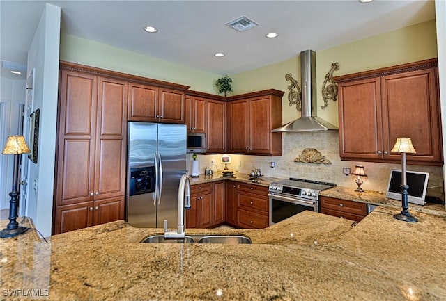 kitchen with sink, light stone countertops, wall chimney exhaust hood, and appliances with stainless steel finishes