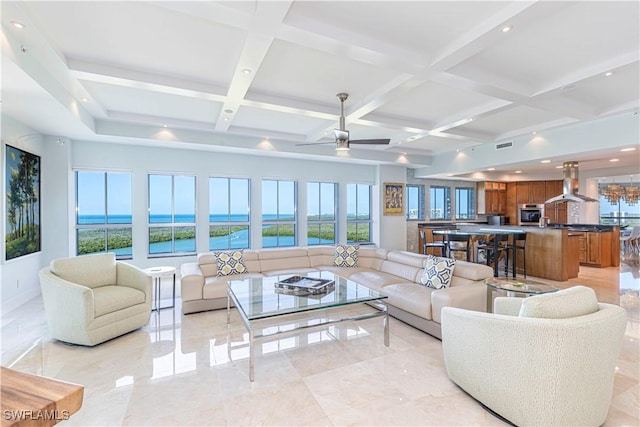 living room with a water view, ceiling fan, plenty of natural light, and beam ceiling