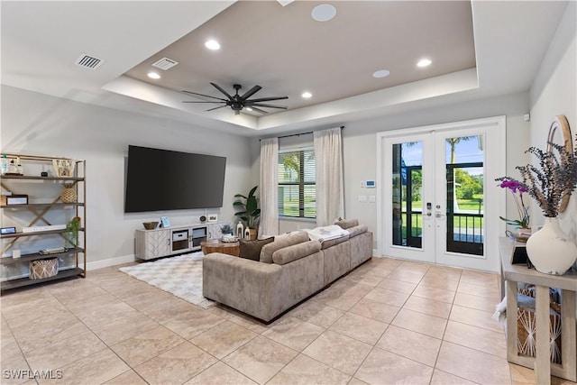 tiled living room with french doors, a raised ceiling, and ceiling fan