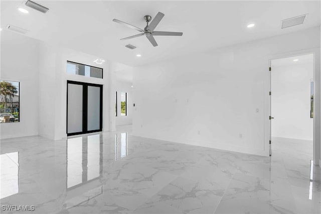 spare room featuring ceiling fan, a healthy amount of sunlight, and a high ceiling