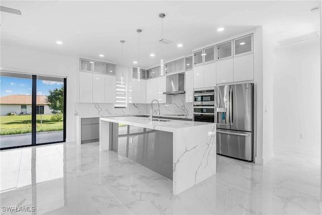 kitchen featuring stainless steel refrigerator with ice dispenser, sink, exhaust hood, a center island with sink, and white cabinets