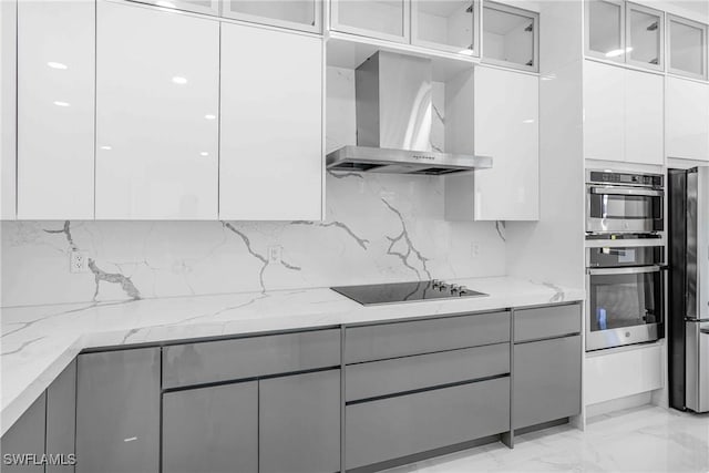 kitchen featuring appliances with stainless steel finishes, light stone counters, gray cabinetry, wall chimney range hood, and white cabinets