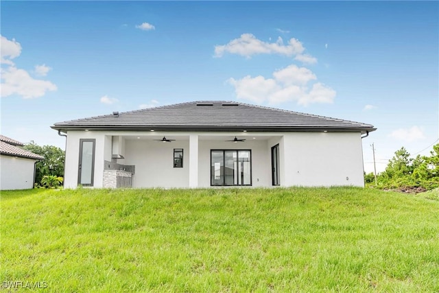 rear view of house with ceiling fan and a lawn