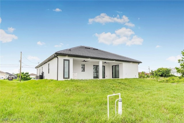 back of house with ceiling fan and a yard