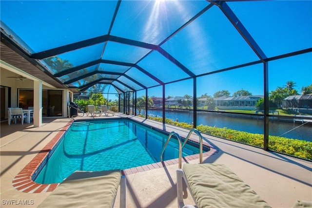 view of swimming pool with a patio, a water view, ceiling fan, and glass enclosure