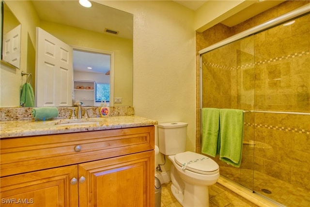 bathroom featuring vanity, toilet, tile patterned flooring, and a shower with door