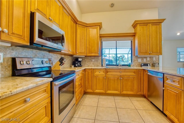 kitchen featuring sink, plenty of natural light, light stone countertops, and appliances with stainless steel finishes